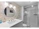 Bright bathroom featuring a glass enclosed shower, white tile, and a stone accent wall at 5955 Blue Sage Way, Littleton, CO 80123