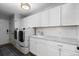 Modern laundry room with white cabinetry, stainless steel washer and dryer, and a convenient sink at 5955 Blue Sage Way, Littleton, CO 80123