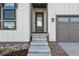 Inviting front entrance featuring a gray door, concrete steps, and decorative rock landscaping at 11492 Stonewash St, Littleton, CO 80125