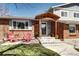 Inviting front porch with covered entry, brick facade, and cozy seating area with bright chairs at 13915 W 73Rd Ave, Arvada, CO 80005