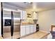 Basement kitchenette with stainless steel refrigerator and bright white cabinetry at 13915 W 73Rd Ave, Arvada, CO 80005