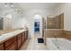 Well-lit bathroom featuring a double vanity, a walk-in shower with tiled surround, and a soaking tub at 11307 Navajo Cir # A, Westminster, CO 80234