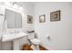 Simple powder room featuring a pedestal sink, a toilet, artwork, and wood floors at 703 Tiger Lily Way, Highlands Ranch, CO 80126