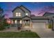Beautiful two-story home with a welcoming front porch and well-maintained landscaping at dusk at 703 Tiger Lily Way, Highlands Ranch, CO 80126