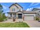 Charming two-story home with a covered front porch, featuring stone accents and a two-car garage at 703 Tiger Lily Way, Highlands Ranch, CO 80126