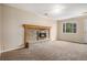 Cozy living room featuring a charming stone fireplace with wooden mantle, carpet flooring, and ample natural light at 4906 E Bates Ave, Denver, CO 80222