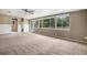Spacious living area with a wall of windows overlooking the backyard, neutral carpet and walls, and a ceiling fan at 4906 E Bates Ave, Denver, CO 80222