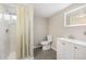 Bright bathroom featuring a shower with a cream shower curtain, toilet, sink, and illuminated mirror at 1920 Elmira St, Aurora, CO 80010