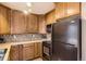 Compact kitchen featuring wooden cabinets, black appliances, and a tile backsplash at 3866 S Dallas Cir # 12202, Aurora, CO 80014