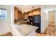 Compact kitchen featuring wooden cabinets, black appliances, and a tile backsplash at 3866 S Dallas Cir # 12202, Aurora, CO 80014