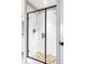 Modern shower featuring sleek tile walls, pebble floor, and a contemporary black frame glass door at 577 Tristan Pl, Berthoud, CO 80513