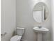 Small, modern bathroom featuring a pedestal sink, toilet, and round mirror at 1836 Westport Ave, Berthoud, CO 80513