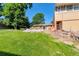Lush backyard featuring a grassy lawn, mature trees and the home's exterior with a quaint patio at 7930 S Kendall Ct, Littleton, CO 80128