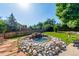 Beautiful backyard featuring rock water feature, complemented by green lawn and stone patio at 7930 S Kendall Ct, Littleton, CO 80128