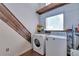 Functional laundry room with washer, dryer, wooden accents, and storage shelves at 7930 S Kendall Ct, Littleton, CO 80128