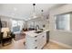 Bright open-concept kitchen featuring white cabinets, island with sink, and stainless steel appliances at 1473 N Locust St, Denver, CO 80220