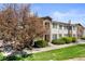 Exterior shot of a two-story townhome with mature trees, green lawn and landscaping at 8615 W Berry Ave # 203, Littleton, CO 80123