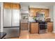 Well-lit kitchen featuring stainless steel appliances, wood cabinets and tile backsplash at 9787 W Ohio Ave, Lakewood, CO 80226