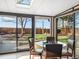 Enclosed sunroom with a glass table and chairs overlooking a well-manicured backyard at 9787 W Ohio Ave, Lakewood, CO 80226