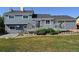 Back of the home with a wooden deck surrounded by green landscaping at 21518 E Powers Ln, Centennial, CO 80015