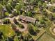 Aerial view of a brick home with a wooden deck, surrounded by trees and a winding driveway at 5460 S Olive St, Greenwood Village, CO 80111