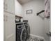 Bright laundry room with white cabinetry, patterned tile floor, and modern front-loading washer and dryer at 15776 Native Willow Dr, Monument, CO 80132