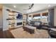 Open living room with fireplace, media center, ceiling fan, and large windows showcasing the exterior view at 15776 Native Willow Dr, Monument, CO 80132