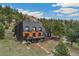 Daytime exterior of modern mountain home, featuring a large deck and surrounding landscape at 6640 Kilimanjaro Dr, Evergreen, CO 80439