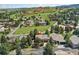 Aerial view of a residential home with surrounding trees and lush landscape in a golf course community at 6457 Willow Broom Trl, Littleton, CO 80125