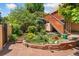 Serene backyard with stone patio, tiered garden beds, steps to the second story, and lush landscaping at 6457 Willow Broom Trl, Littleton, CO 80125