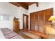 Cozy bedroom with wood beamed ceiling, terracotta floors, closet, and rustic decor at 6457 Willow Broom Trl, Littleton, CO 80125