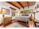 Inviting bedroom featuring wood beamed ceiling, terracotta floors, colorful bedding, and rustic decor at 6457 Willow Broom Trl, Littleton, CO 80125