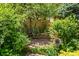Secluded courtyard featuring a brick patio, mature greenery, and a peaceful garden bench at 6457 Willow Broom Trl, Littleton, CO 80125
