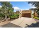 This tan home features a large driveway, wood garage door, and Southwestern architectural details at 6457 Willow Broom Trl, Littleton, CO 80125