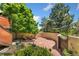Charming stone patio with a curved wall, lush garden, mature shade trees, and inviting outdoor seating at 6457 Willow Broom Trl, Littleton, CO 80125