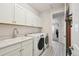 Well-lit laundry room features a sink, cabinets, and modern washer and dryer at 171 S Waterloo St, Aurora, CO 80018