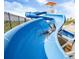 Personal enjoying the summer heat by riding down a long blue water slide on a sunny day at 171 S Waterloo St, Aurora, CO 80018