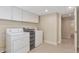Well-lit laundry room with white washer and dryer, storage cabinets and beige walls at 20271 E Lake Ave, Centennial, CO 80016