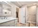 Modern bathroom with stylish vanity, well-lit mirror, and a door to an adjacent area at 15437 W 95Th Ave, Arvada, CO 80007