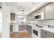Updated kitchen boasts grey cabinetry, subway tile backsplash, white appliances, and wood-look flooring at 1279 S Sable Blvd, Aurora, CO 80012