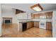 A warm kitchen with wood floors, cabinets, a breakfast bar, and a view of a fireplace and second-story walkway at 5276 S Danube St, Centennial, CO 80015