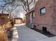 A brick home exterior with an expansive concrete patio leading to the detached garage in a quiet neighborhood at 1378 Forest St, Denver, CO 80220