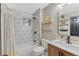 Bathroom boasting a shower-tub combination with patterned wall, vanity, sink, and shelves at 13053 Umatilla Ct, Denver, CO 80234