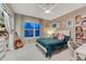Bright bedroom with a plush teal bedspread, a large window, a ceiling fan, and ample closet space at 13053 Umatilla Ct, Denver, CO 80234