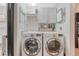 Modern laundry room featuring front load washer and dryer with white cabinets and neutral wallpaper at 13053 Umatilla Ct, Denver, CO 80234