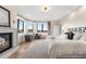 Spacious primary bedroom featuring fireplace, seating area with natural light, and a king bed with luxury bedding at 8240 W Tennessee Ave, Lakewood, CO 80226
