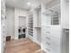 Walk-in closet with custom shelving and drawers, featuring hardwood floors and adjacent laundry room with washer and dryer at 8240 W Tennessee Ave, Lakewood, CO 80226