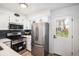Modern kitchen boasts stainless steel appliances, white cabinets, and stylish black backsplash at 3231 S Estes St, Lakewood, CO 80227