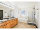 Well-lit bathroom with double sink vanity, walk-in shower, and soaking tub at 4844 Mt Evans St, Brighton, CO 80601