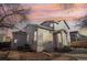 A charming gray two-story home with a brick pathway and a detached garage under a colorful sky at 4844 Mt Evans St, Brighton, CO 80601